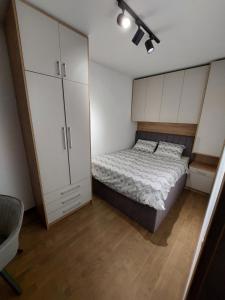 a small bedroom with a bed and white cabinets at Apartman M 21 in Karaburma +19 photos