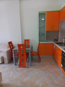 ヴロラにあるLungomare Apartament Sea view KORALのキッチン(オレンジ色のキャビネット、テーブル、椅子付)