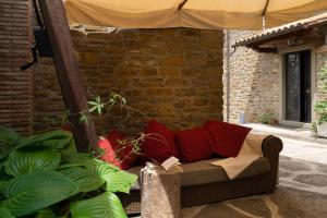 a couch with red pillows sitting under an umbrella at Buccia Nera in Chiassa Superiore