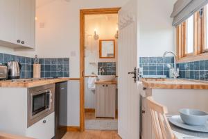 a kitchen with blue tiled walls and a sink at Outbak Shepherds Hut in Cheltenham