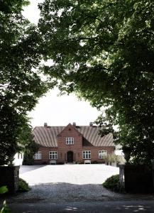 una gran casa de ladrillo rojo con una gran entrada en The Norrmans Farmhouse Boutique Hotel, en Klippinge