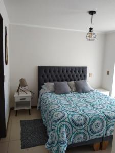 a bedroom with a bed with a blue and green quilt at Departamento sector Cavancha in Iquique