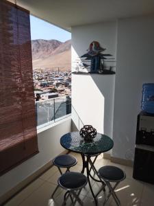 - une table et des tabourets dans une chambre avec vue sur la ville dans l'établissement Departamento sector Cavancha, à Iquique