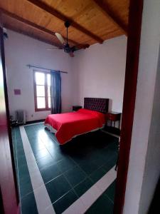 a bedroom with a red bed and a window at CASA QUINTA LA ENCANTADA in San Miguel de Tucumán