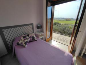 - une chambre avec un lit violet et un balcon dans l'établissement Il Giardino delle Zagare, à Fondi