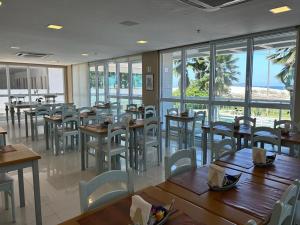 a restaurant with wooden tables and chairs and windows at MANDAI Apartamento Cabo Frio in Cabo Frio
