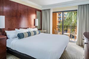 a bedroom with a large white bed and a balcony at The Atlantic Suites on the Ave in Delray Beach