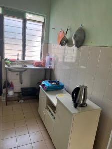 uma pequena cozinha com um lavatório e um balcão em Maju Homestay em Gerik