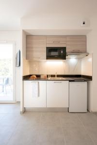 a kitchen with white cabinets and a microwave at Résidence Pierre et Vacances Cap Cassis Calanques in Roquefort-la-Bédoule +46 photos
