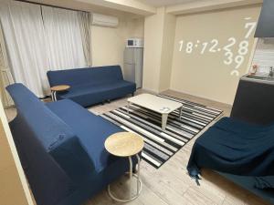 a living room with blue couches and a table at Sincere Residence in Osaka