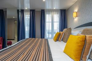 1 dormitorio con 1 cama grande con almohadas amarillas en Hôtel Du Vieux Saule en París