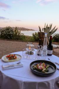 ポルト・ヴェッキオにあるHôtel & Lodges Moby Dickのテーブル(2皿の食べ物とワイングラス付)