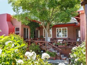 una casa con terraza y un árbol en Gumtree Guest House, en Oudtshoorn