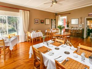 uma sala de jantar com mesas e cadeiras brancas em Gumtree Guest House em Oudtshoorn