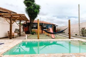 a pool with a hammock and a house at Casa c conforto piscina e churrasqueira Atibaia in Atibaia