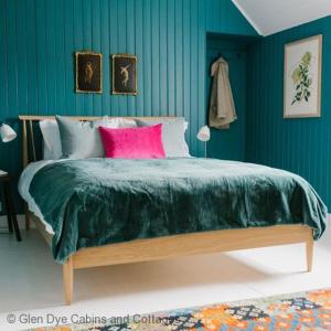 a green bedroom with a large bed with pink pillows at Cuttieshillock in Banchory