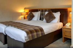 Buchanan Arms Hotel & Leisure Club في دريمن: غرفة في الفندق سرير كبير مع وسادتين