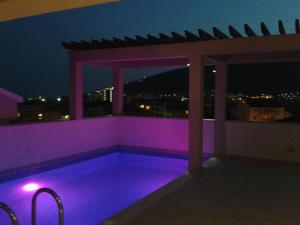 - une piscine avec éclairage violet sur un balcon la nuit dans l'établissement Apartments and Rooms Grand Palazzo, à Budva