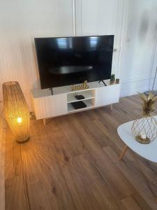 ein Wohnzimmer mit einem Flachbild-TV und einem Tisch in der Unterkunft LE GALET BLANC cosy T2 en centre ville du Havre in Le Havre