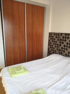 a bedroom with a white bed with a wooden closet at Confortable departamento. Muy buena ubicacion in Zárate