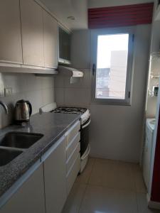 a kitchen with a stove and a sink and a window at Confortable departamento. Muy buena ubicacion in Zárate