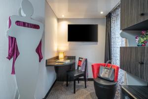 a hotel room with a desk and a tv at Hôtel Du Vieux Saule in Paris
