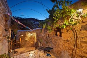 um pátio com uma mesa e cadeiras numa parede de pedra em Natura cottages em Makry Gialos