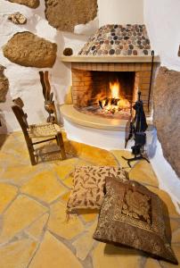 um quarto com lareira e uma mesa com almofadas em Natura cottages em Makry Gialos