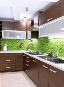 a kitchen with brown cabinets and green tiles at ClickTheFlat Piękna Center Apart Rooms in Warsaw