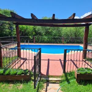 um jardim com uma piscina e uma pérgola em Cabañas SHAMBALLA em Cafayate