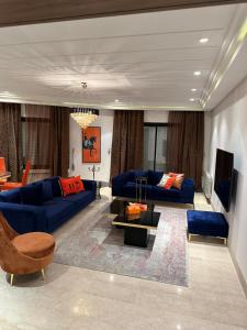 un salon avec des canapés bleus et une télévision dans l'établissement S+3 luxurious apartment Hermes design in les jardins de Carthage Lac2, à Sidi Daoud