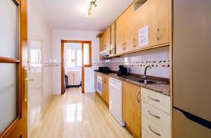una cucina con elettrodomestici bianchi e armadietti in legno di La Manga 2 Bedroom Apartment near the Beach a Murcia
