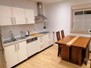 cocina con armarios blancos y mesa de madera en Apartment Home 1, en Schwabach