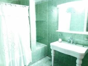 baño de azulejos verdes con lavabo y ducha en CASA QUINTA LA ENCANTADA en San Miguel de Tucumán