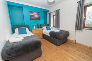 Duas camas num quarto com paredes azuis em Business friendly & Spacious 2BR home - Perfectly located for working in Swansea em Swansea