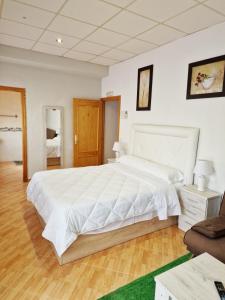 a large white bedroom with a large bed and a chair at Hostal El Brillante - Alojamientos El Duque in Córdoba