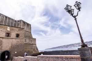 una luz de la calle frente a un castillo en Le 4 Stagioni Dante's Suites H Napoli Centro, by ClaPa Group, en Nápoles