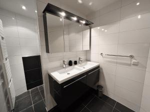een witte badkamer met een wastafel en een spiegel bij Hello Zeeland - Appartement Loverendale 10 in Domburg