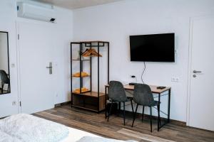 a room with a desk with two chairs and a television at Dill Hotel in Ilsede