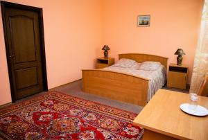 Schlafzimmer mit einem Bett, einem Tisch und einem Teppich in der Unterkunft Avalon in Krementschuk
