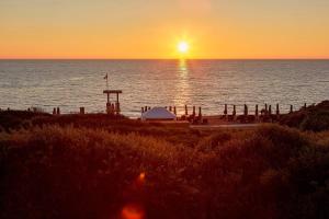 a sunset on a beach with the sun setting over the water at The Westin Resort, Costa Navarino in Romanu