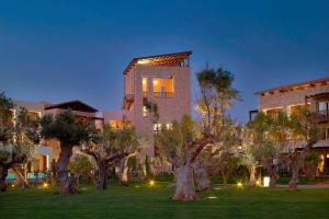 een gebouw met een bos bomen ervoor bij The Westin Resort, Costa Navarino in Romanu