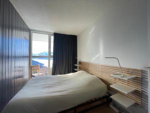 sypialnia z łóżkiem i dużym oknem w obiekcie Homency - Résidence le Sanghri-La w LʼAlpe-dʼHuez