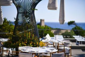 a restaurant with tables and chairs and a large plant at The Westin Resort, Costa Navarino in Romanu