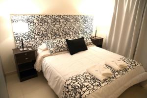 1 dormitorio con 1 cama con cabecero blanco y negro en Soho Apart- en el corazon de la ciudad en Venado Tuerto