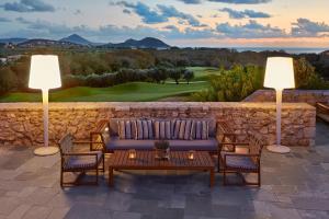 a patio with a couch and two lights on a wall at The Westin Resort, Costa Navarino in Romanu