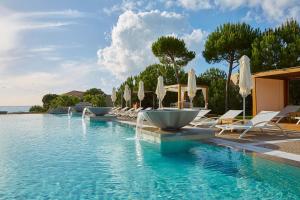 a swimming pool with lounge chairs and umbrellas at The Westin Resort, Costa Navarino in Romanu
