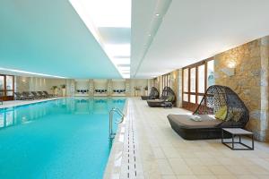 a pool in a hotel room with chairs at The Westin Resort, Costa Navarino in Romanu