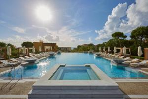a large swimming pool with lounge chairs and a swimming pool at The Westin Resort, Costa Navarino in Romanu