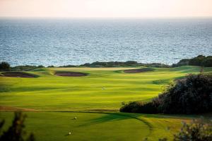 a green golf course with the ocean in the background at The Westin Resort, Costa Navarino in Romanu